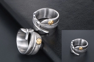 Close-up of vintage silver feather ring with detailed texture and gold cross emblem