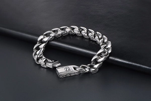 Detailed close-up of silver steel curb bracelet featuring retro engraved pattern on the clasp