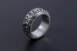 Détail macro d'une bague vintage en acier avec motifs de feuilles et fleurs gravées