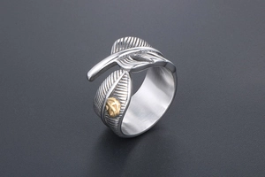 Detailed view of silver feather ring featuring a gold eagle crest with oxidized texture