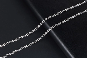 Macro shot of polished silver titanium steel cable chain on black textured background