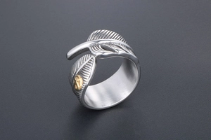 Detailed close-up of retro feather ring featuring silver texture and gold bird accent