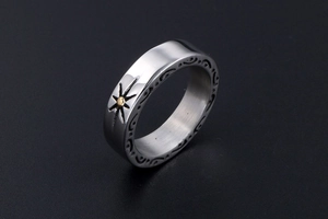 Detail of vintage steel ring featuring golden sun relief and black scroll engraving