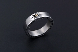 Detailed close-up of vintage steel ring with sunburst pattern and golden center bead