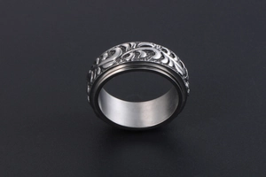 Gros plan de la bague rotative en acier inoxydable vintage avec motifs de feuilles