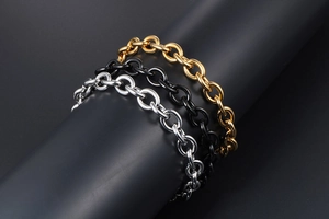 Macro shot of minimalist three-color titanium steel chain bracelets in gold, black, and silver