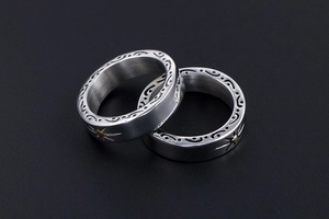 Macro detail of silver vintage titanium steel rings with sunflower patterns on dark background