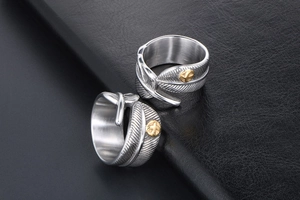 Detail of vintage silver feather rings with gold embossed accents on black leather