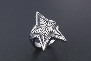 Macro shot of silver retro star ring featuring detailed radial grooves and punk textures