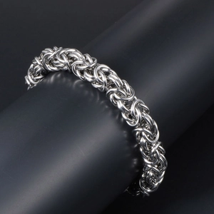 Men's silver-tone Byzantine woven steel bracelet on a black minimalist display