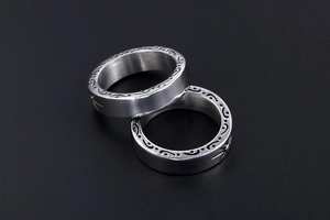 Macro shot of polished titanium steel rings featuring side sun flower pattern engraving
