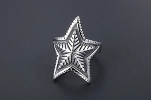 Macro shot of silver vintage star ring featuring detailed radial texture and punk style