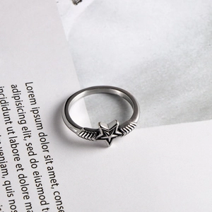 Anillo de estrella vintage en metal plateado con alas estilo punk en papel rústico