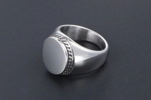 Macro view of wide signet ring with flat circular mirror surface and engraved wave edges