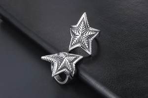 Detailed close-up of two silver star rings with textured metal surfaces on black leather