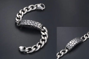 Macro view of silver titanium steel bracelet with textured pebble pattern on curb chain