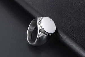 Detail shot of a silver signet ring with braided edges on a black leather background