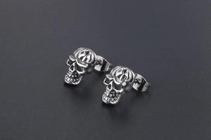 Vue détaillée de clous d'oreilles tête de mort en acier titane avec texture punk argentée