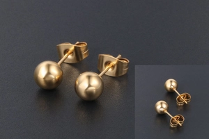 Gros plan détaillé de boucles d'oreilles boules dorées polies avec fermoirs papillon