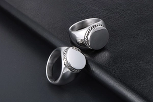 Detail of silver titanium steel signet ring with braided rope border on leather background