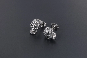 Gros plan de boucles d'oreilles tête de mort vintage avec gravure punk en argent antique