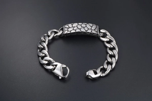 Macro detail of silver titanium steel curb chain bracelet with stone texture plaque