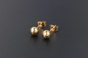 Vue détaillée des boucles d'oreilles boules dorées avec fermoirs papillon et fini miroir poli