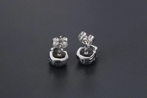Vue macro des boucles d'oreilles tête de mort en acier avec structure arrière et texture argent