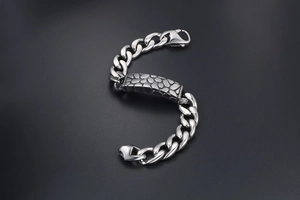 Detailed macro view of pebble texture on stainless steel curb chain bracelet