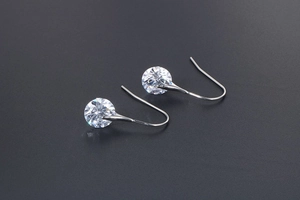 Macro view of crystal stud earrings with shiny round stones and silver hook clips
