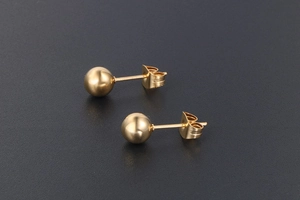 Gros plan de boucles d'oreilles boules dorées polies avec fermoir papillon classique