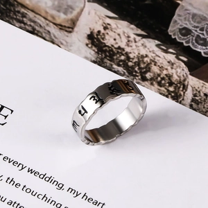 Detailed view of the wavy edge stainless steel ring with black engraved mantras symbols