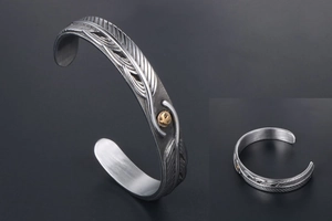 Macro detail of retro feather engraving and golden eagle emblem on silver metal cuff