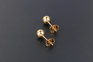 Gros plan de boucles d'oreilles sphériques dorées en acier titane avec finition polie et fermoirs