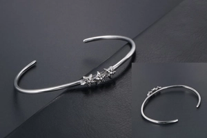 Détail d'un bracelet en acier argenté en forme de C avec trois étoiles texturées