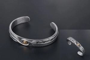 Macro detail of vintage eagle feather bangle with gold sun emblem in retro silver finish
