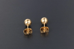 Vue macro de boucles d'oreilles boules en acier titane doré avec fermoir papillon