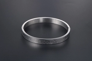 Macro view of Heart Sutra laser engraved on polished silver stainless steel bangle