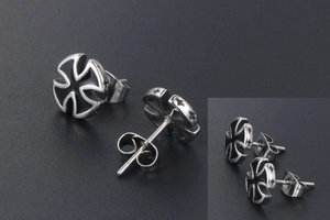 Macro detail of titanium cross earrings featuring black enamel and star engraved edges