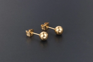 Gros plan sur des boucles d'oreilles boules dorées polies avec fermoirs papillon