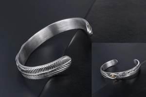 Detail of silver feather cuff bracelet featuring a vintage golden eagle sun emblem
