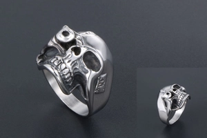 Macro detail of silver one-eyed skull ring in polished stainless steel gothic style