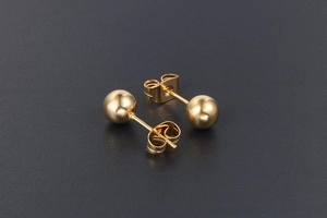 Gros plan de boucles d'oreilles boules dorées en acier titane avec fermoirs papillon
