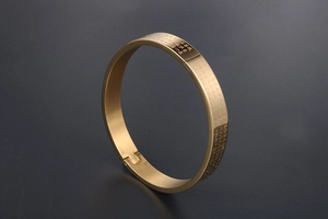 Close-up of gold-plated stainless steel bangle with engraved Buddhist Heart Sutra script