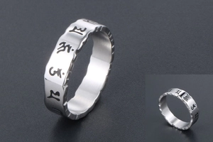 Macro view of men's vintage steel ring with wave edges and engraved mantra symbols