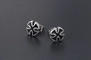 Close-up of silver and black stainless steel cross earrings with gothic enamel design
