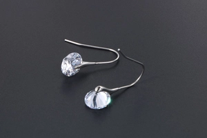 Macro shot of silver drop earrings with faceted clear crystals on a sleek grey background