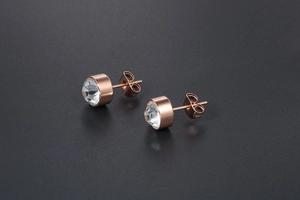 Detail of rose gold cylinder stud earrings with faceted clear crystal and butterfly back