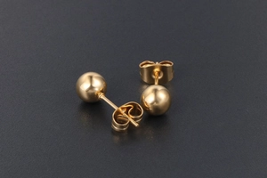 Gros plan détaillé d'une paire de boucles d'oreilles boules dorées polies avec fermoirs