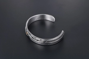 Detailed macro shot of vintage feather patterns on an adjustable titanium steel cuff bracelet